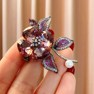 Detailed view of flower brooch with purple crystals and a white freshwater pearl