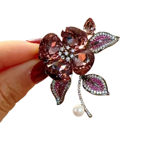 Elegant flower brooch with purple crystals and white freshwater pearl on white background