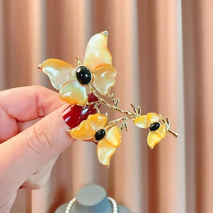 Elegante spilla a farfalla con intarsio in conchiglia naturale e gemma nera su tessuto