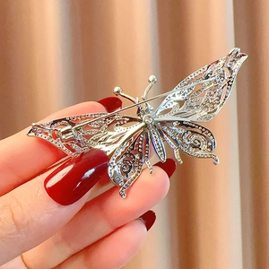 Détail d'une broche papillon argentée avec cristaux micro-pavés et design filigrane évidé