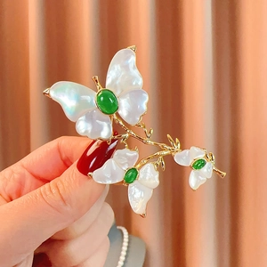 Elegante spilla a farfalla in conchiglia naturale con gemma verde e oro