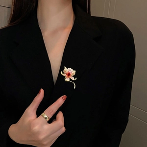 Spilla a fiore orchidea elegante con petali rosa e zircone rosso su blazer nero