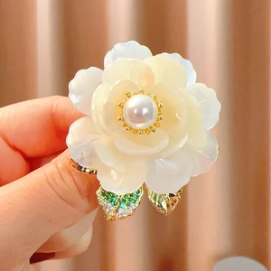 Gros plan détaillé d'une broche pivoine en nacre naturelle avec une perle centrale