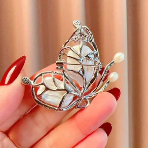 Detail view of butterfly brooch featuring baroque pearls and silver hollow metalwork