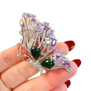 Elegant butterfly brooch with purple and green crystals on a silver metal base