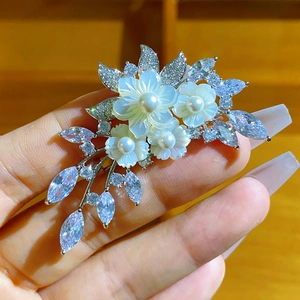Dettaglio di spilla a fiore con petali di conchiglia naturale, perle e zirconi cubici