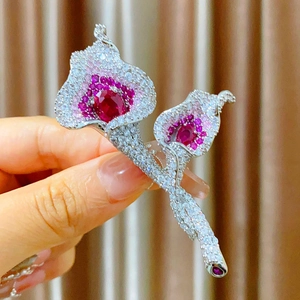 Macro view of Calla Lily brooch with pavé zircon settings and red gemstone centers