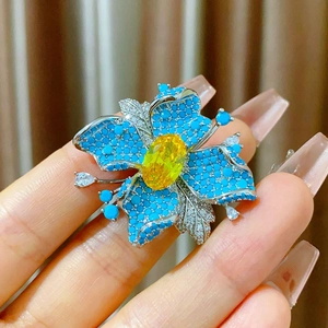 Détail de la broche fleur aimantée avec pierre jaune et pétales en pavé bleu
