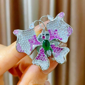 Elegant butterfly brooch with purple zircons and green central stone on silver metal