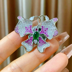 Detail of butterfly magnet brooch with purple zircons and green cabochon center stone
