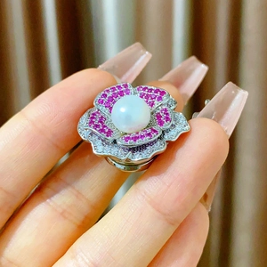 Gros plan d'une broche camélia magnétique avec perle blanche et zircons roses