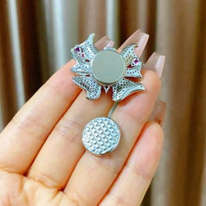 Détail macro de la broche papillon avec zircons rouges et fermoir magnétique argenté