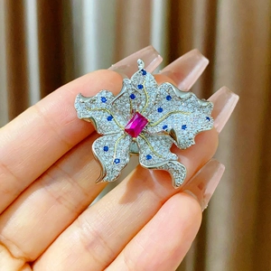 Detail der Blumenbrosche mit rotem Mittelstein und blauen Kristallen auf Silberblüten