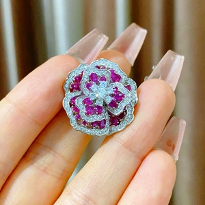 Macro shot of silver flower brooch with red zircon petals and magnetic clasp detail