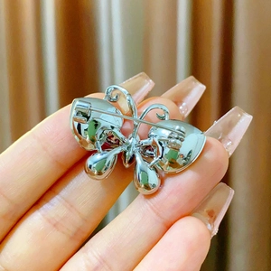 Detail of butterfly brooch back showing silver metal plating and secure pin fastening
