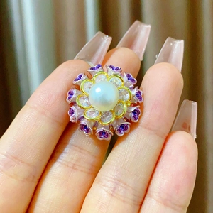 Détail de la bague fleur avec perle blanche, pétales en émail violet et fini doré