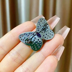 Detail of the butterfly brooch back with blue and purple gems on a gun-black metal base