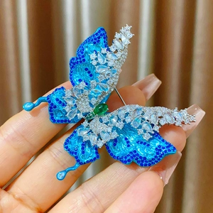 Primer plano del broche de mariposa azul con circonitas y piedra preciosa verde central