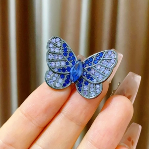 Detailed close-up of a luxury butterfly brooch featuring blue and purple gemstones