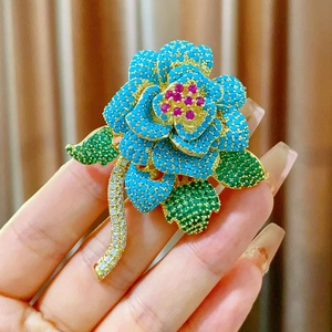 Dettaglio della spilla a fiore vintage con petali turchesi e gemma rosa centrale
