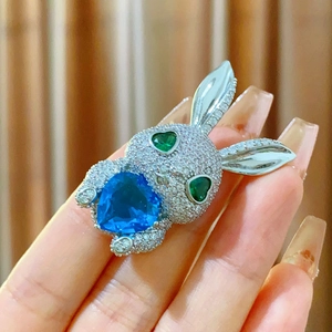 Broche lapin étincelante avec yeux en cœur vert et un grand zircon bleu en cœur
