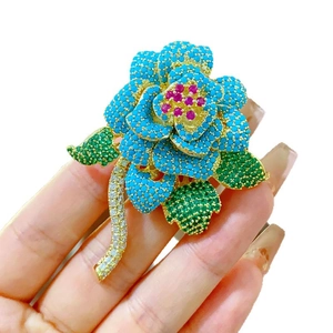 Lussuosa spilla a fiore con petali blu e cristalli verdi incastonati su base dorata