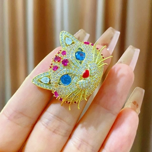 Bague chat dorée avec yeux en zircon bleu et cristaux pavés sur fond de tissu texturé