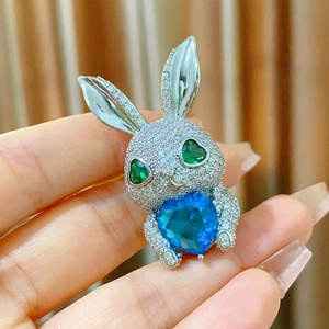Détail d'une broche lapin argentée avec pierre cœur bleue et yeux en zircon vert