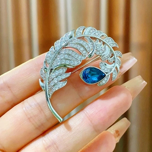 Exquisite silver feather brooch with blue teardrop gemstone and micro-pave crystals