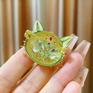 Détail du dos d'une broche chat dorée avec fermoir de sécurité et pierres précieuses