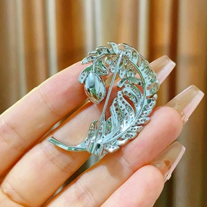 Close-up of the silver feather brooch back showing the secure pin clasp and metal texture