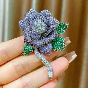 Elegant purple rose brooch with cubic zirconia crystals held by hand for scale
