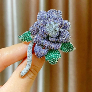 Close-up of elegant purple rose brooch with inlaid zircons and green crystal leaves