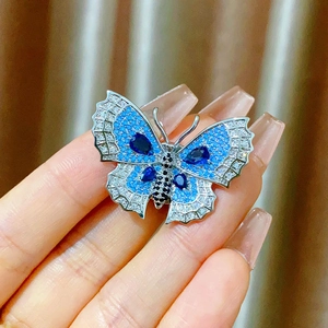 Close-up of butterfly brooch featuring blue crystals and silver metallic edges