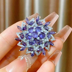Macro shot of luxury snowflake brooch with purple zircon and pavé diamonds held by hand