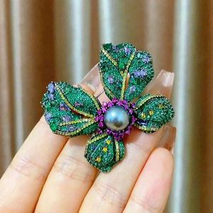 Detailed view of luxury flower brooch with colorful micro-pave zircons and a grey pearl