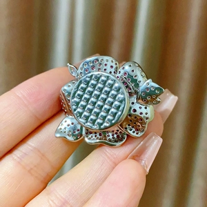 Detail of vintage flower brooch featuring red crystals and a silver domed mesh center