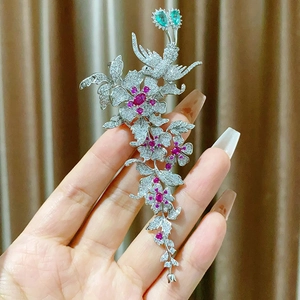 Élégante broche fleur et pie avec pavé de zircons et rubis sur fond brun plissé