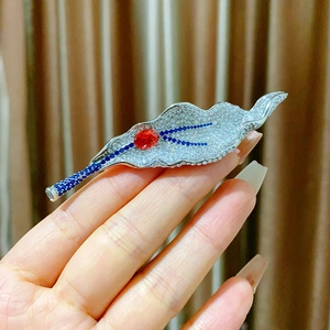 Detailed shot of a silver leaf brooch with micro-pave zircon and red center stone