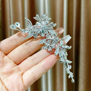 Détail d'une broche fleurie en alliage argenté avec zircons et pierres précieuses colorées