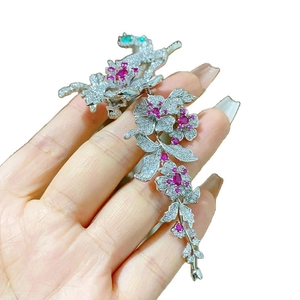Broche fleur de pie élégante avec pampilles en zircon tenue à la main sur blanc