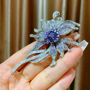 Macro detail of silver flower brooch with purple zircon micro-inlay and emerald accents