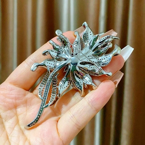 Detail view showing the secure back pin clasp and hollow metal craft of flower brooch