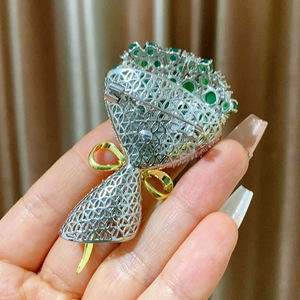 Détail macro de la broche fleur de trompette avec zircons émeraude et ajourage argenté