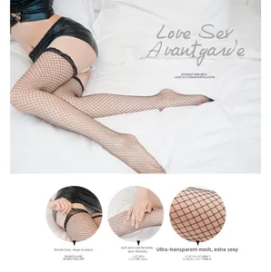 Detail view of black fishnet stockings featuring elastic floral lace top and large mesh