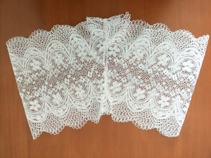 Détail du tissu en dentelle florale blanche avec bords festonnés sur fond en bois noir