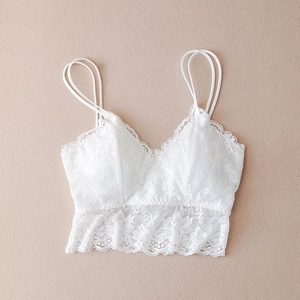 Close-up of intricate floral lace texture on white V-neck camisole with scalloped hem