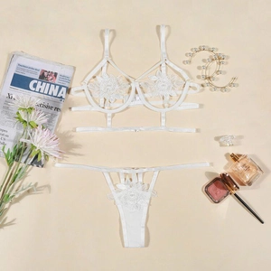 Dettaglio del set lingerie in pizzo bianco con ricami floreali e accessori decorativi