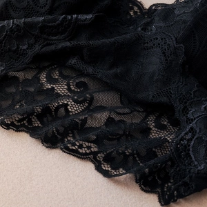 Close-up of intricate black lace fabric showing detailed floral embroidery pattern