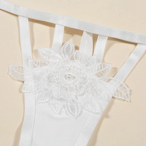 Dettaglio macro di ricamo floreale in pizzo bianco con perla su fascia di lingerie